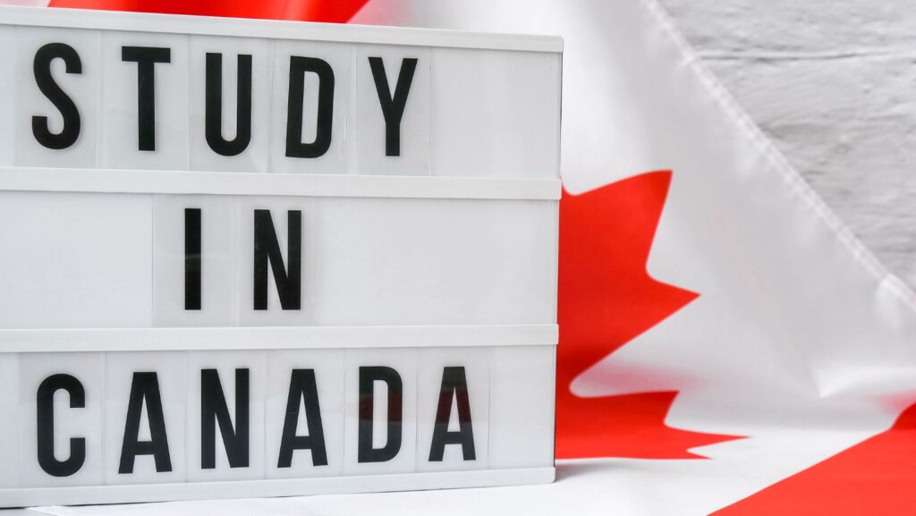 A sign that says "study in Canada" sitting on a flag